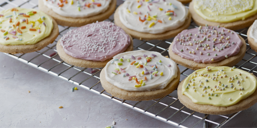 yellow, white, and purple frosting on sugar cookies with various sprinkles