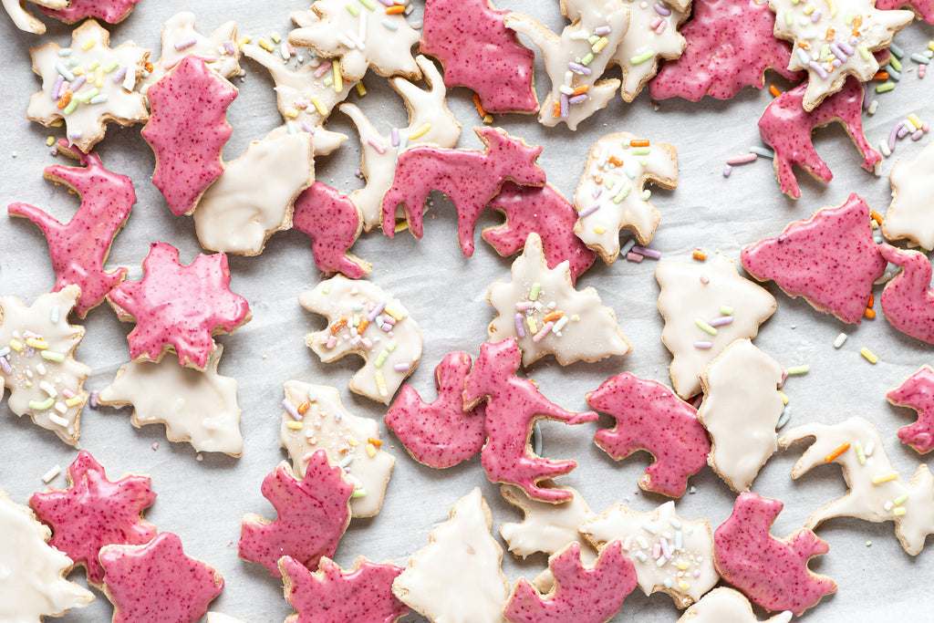homemade grain-free animal crackers on a tray. decorated with white and pink icing and sprinkles.