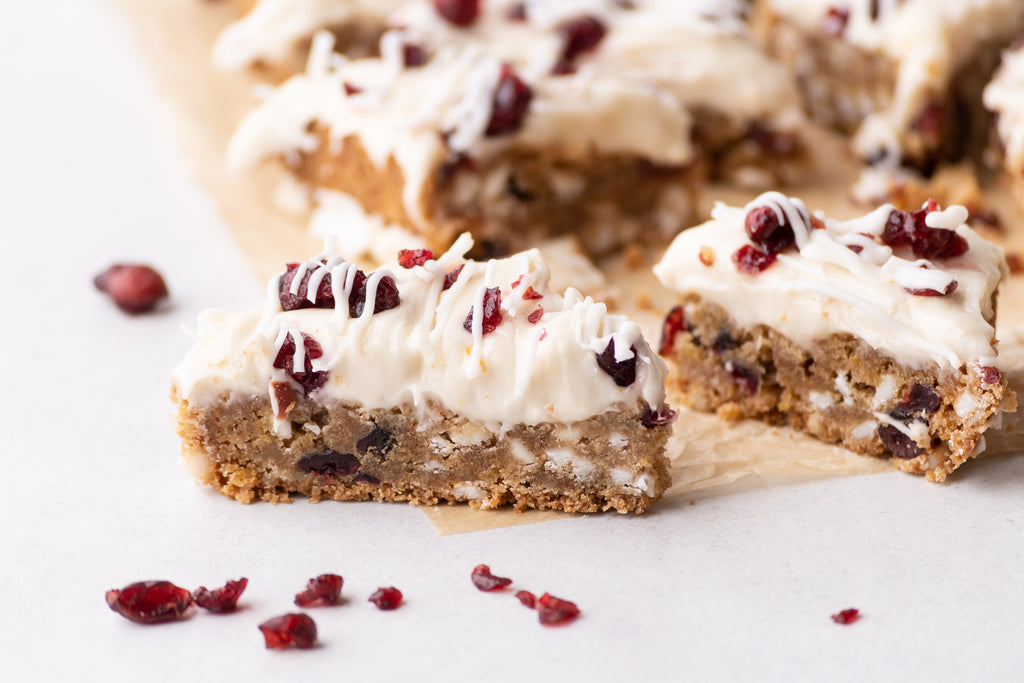 Cranberry-white chocolate blondies with frosting and more dried cranberries and white chocolate on top