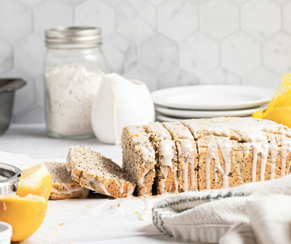 Grain-free lemon poppy seed bread loaf, with glaze on top and cut into slices.