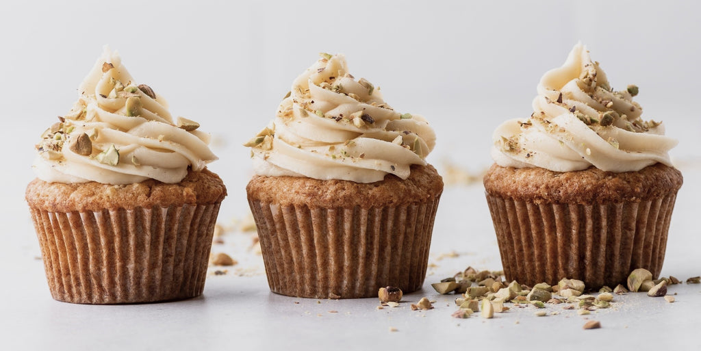 3 carrot cupcakes with icing and chopped nuts